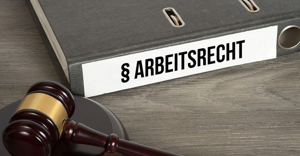 Das Bild zeigt einen Richterhammer und einen Aktenordner mit dem Aufdruck „Arbeitsrecht“ auf einem Tisch.